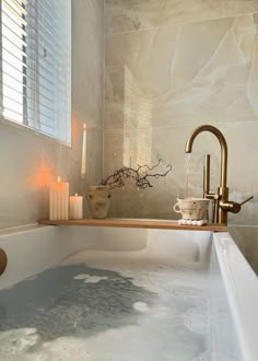 a bathtub filled with water next to candles