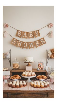 a baby shower dessert table with cupcakes, cookies and bunting banner on the wall