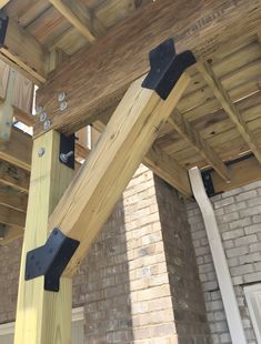 a wooden structure with metal brackets attached to the side of it and brick wall in background