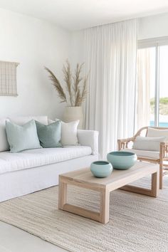a living room filled with white furniture and pillows on top of a rug in front of a window