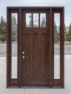 a wooden door with glass panels and sidelights on an empty concrete floor in front of some trees