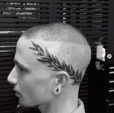 a man with a shaved head has leaves on it's forehead and behind his ear