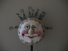 a face painted on the side of a wall next to a pole with a clock