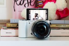 a camera sitting on top of books next to a stuffed bear and teddy bear in the background