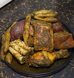 a plate filled with meat and vegetables on top of a black tablecloth covered counter