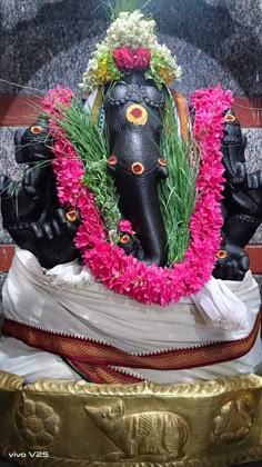 an elephant statue with flowers on its head
