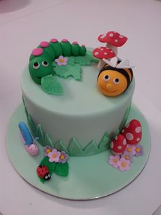 a green cake decorated with bugs and flowers