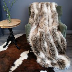 a chair sitting next to a table on top of a cowhide rug in a living room