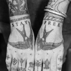 two hands with tattoos that say stay free