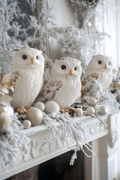 three white owls sitting on top of a mantel covered in snowflakes and balls