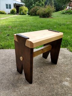 a wooden bench sitting on top of a cement slab in front of a grass covered yard