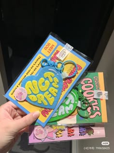 a person holding up two books in their hand, one with an ear tag and the other with stickers on it