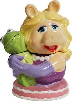 a ceramic figurine of a woman holding a frog on her arm and smiling at the camera