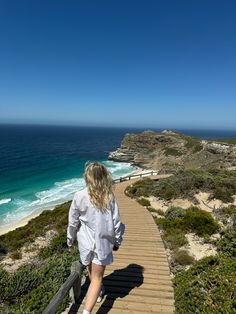 a woman is walking up some stairs to the beach