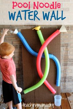 a young boy playing with pool noodles and water wall