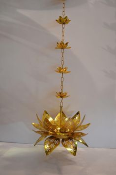a gold chandelier with flowers hanging from it's sides on a chain