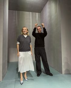 the man and woman are standing in an empty room with their hands up to the sky