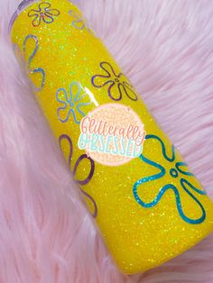 a yellow bottle with blue and purple designs on it sitting on a pink fur covered surface