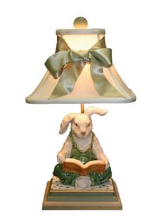 a lamp with a bunny reading a book on it's base and a green bow around the neck