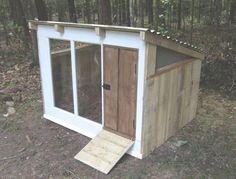 a small outhouse in the woods with doors open