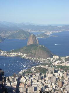 an aerial view of a city with mountains in the background and water on the other side