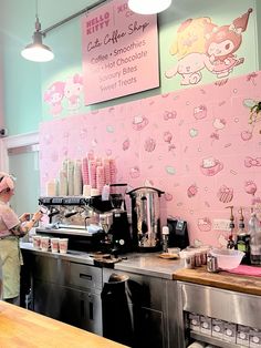 a woman standing in front of a pink wall with hello kitty on it's side