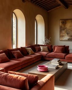 a living room filled with lots of red couches next to tall windows and a painting on the wall