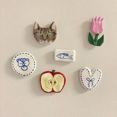 there are several magnets on the wall with cats and flowers attached to each one