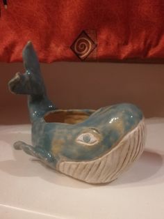 a ceramic animal bowl sitting on top of a white counter next to a red pillow