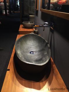 a bowl shaped sink sitting on top of a wooden counter