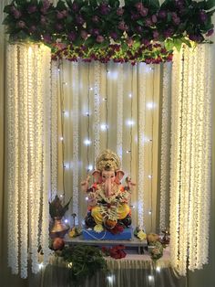 an elephant statue sitting on top of a table under a window covered in flowers and greenery
