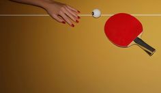 two ping pong paddles and a person's hand reaching for the ball