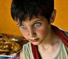 a young boy with blue eyes stares into the camera