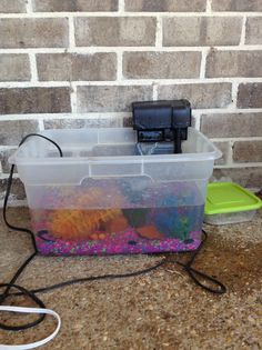 a plastic container filled with water next to a brick wall