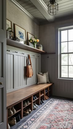 a wooden bench sitting under a window next to a rug and shoes on top of it