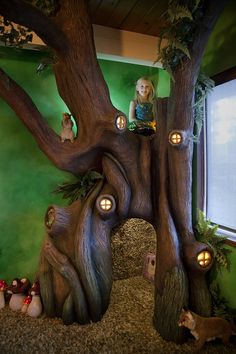 a child is sitting in the middle of a tree with lights on it's branches