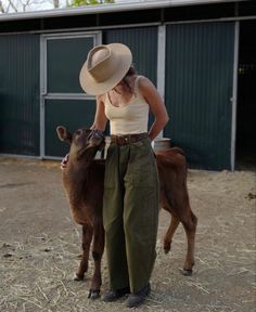 a woman standing next to a brown cow