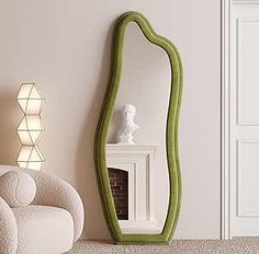 a living room with a white chair and a green mirror on the wall next to a fireplace