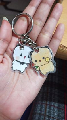 a hand holding a keychain with an image of a person and a teddy bear on it