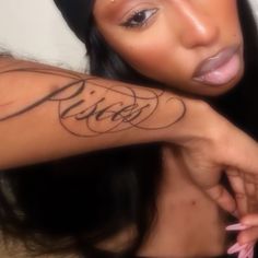 a close up of a person with a tattoo on her arm and the word kiss written in cursive writing