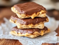 three chocolate covered cookies sitting on top of each other next to a piece of wax paper
