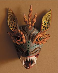 a dragon mask hanging on the wall with it's mouth open and teeth out