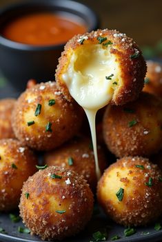 a plate full of cheese balls with sauce being drizzled over them
