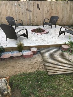a fire pit in the middle of a backyard with chairs around it and a dog laying on the ground