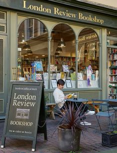 a man sitting at a table in front of a book store