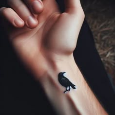 a hand with a small black bird on it's left wrist and the other arm