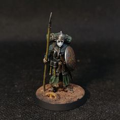 a painted warhammer with a spear and shield on it's head, standing in front of a black background