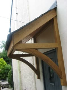a wooden structure hanging from the side of a white building next to a blue door