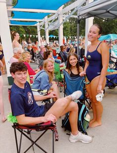 a group of young people sitting around each other in lawn chairs at an outdoor event