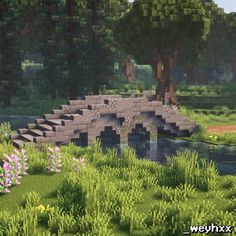 a bridge over a river in a lush green field with trees and flowers on the other side